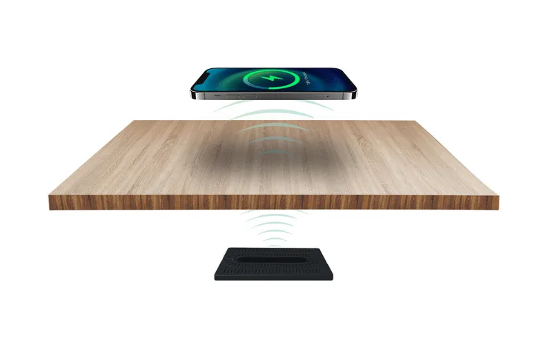 Phone charging above a table with a Stealth wireless charger mounted underneath